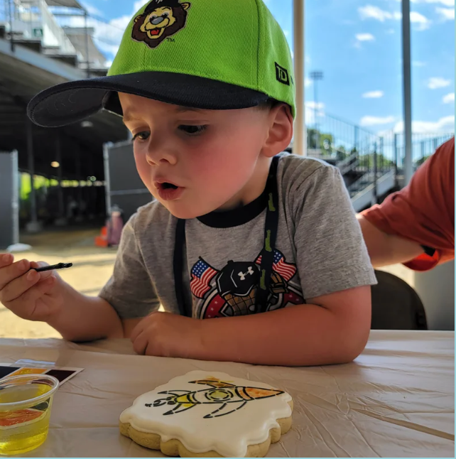 Paint your own cookie featuring a young boy painting a sugar cookie with a rocket on it.