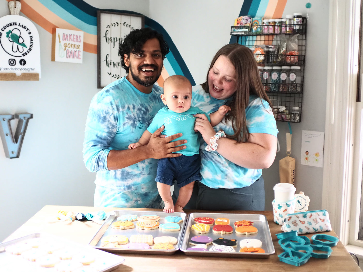 Cookie business owner with husband and baby next to sugar cookies