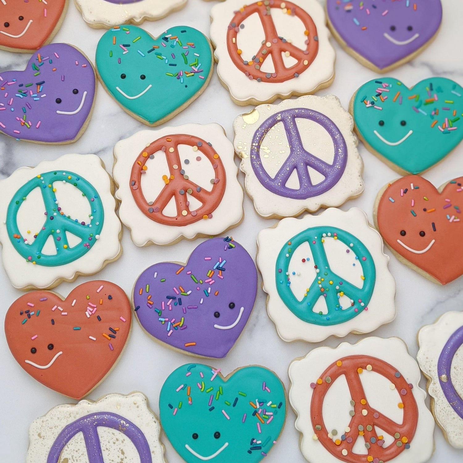 Decorated sugar cookies including hearts smiling and peace signs.